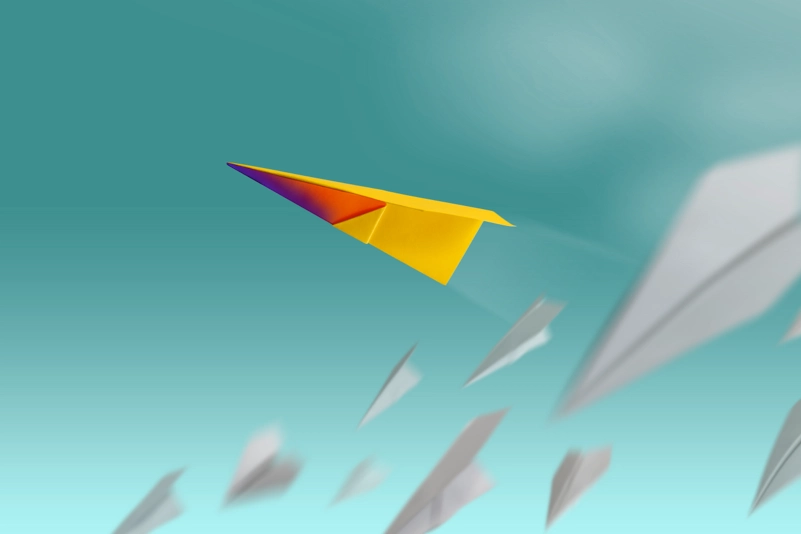 colored paper plane soars while the white colorless ones fall